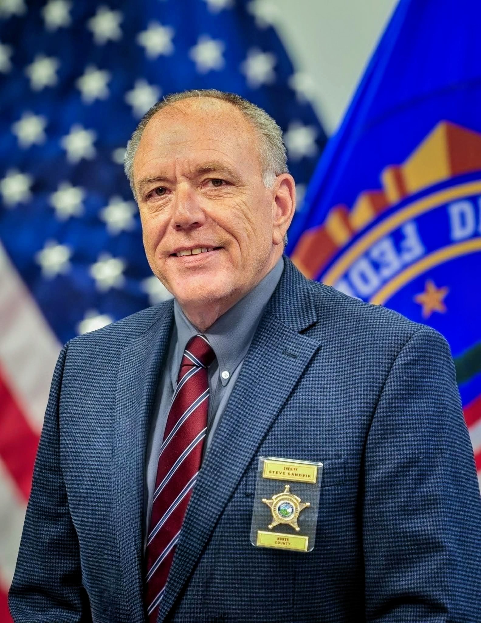 Sheriff Steve Sandvik in official attire with American and Minnesota flags