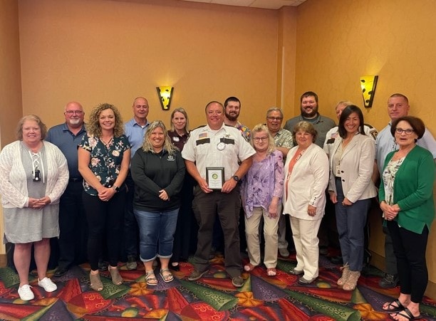 Sheriff Steve Sandvik receiving a service award surrounded by community members and organization representatives in Mower County